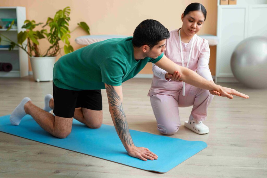 A chiropractor guides a male patient through a quadruped stabilization exercise on a mat for spinal health and rehabilitation.