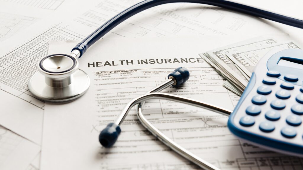 Stethoscope, calculator, and money on a health insurance application form
