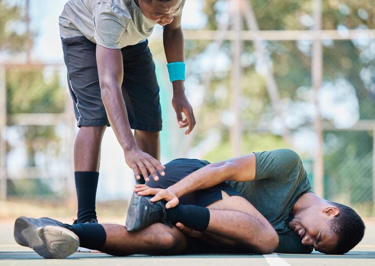 A sports practitioner assists an athlete experiencing acute knee pain and a potential musculoskeletal injury.