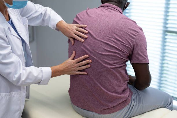 chiropractor examining the back of a male patient in a clinic setting.